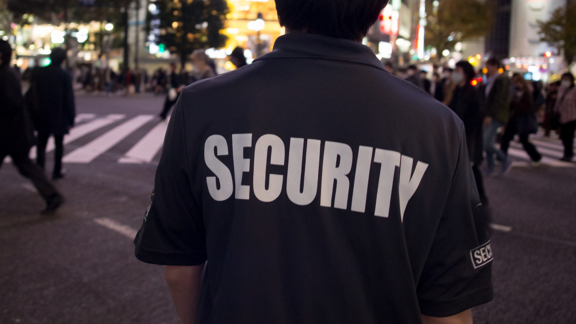 Closeup shot of a security guard walking through the street of the big city at night