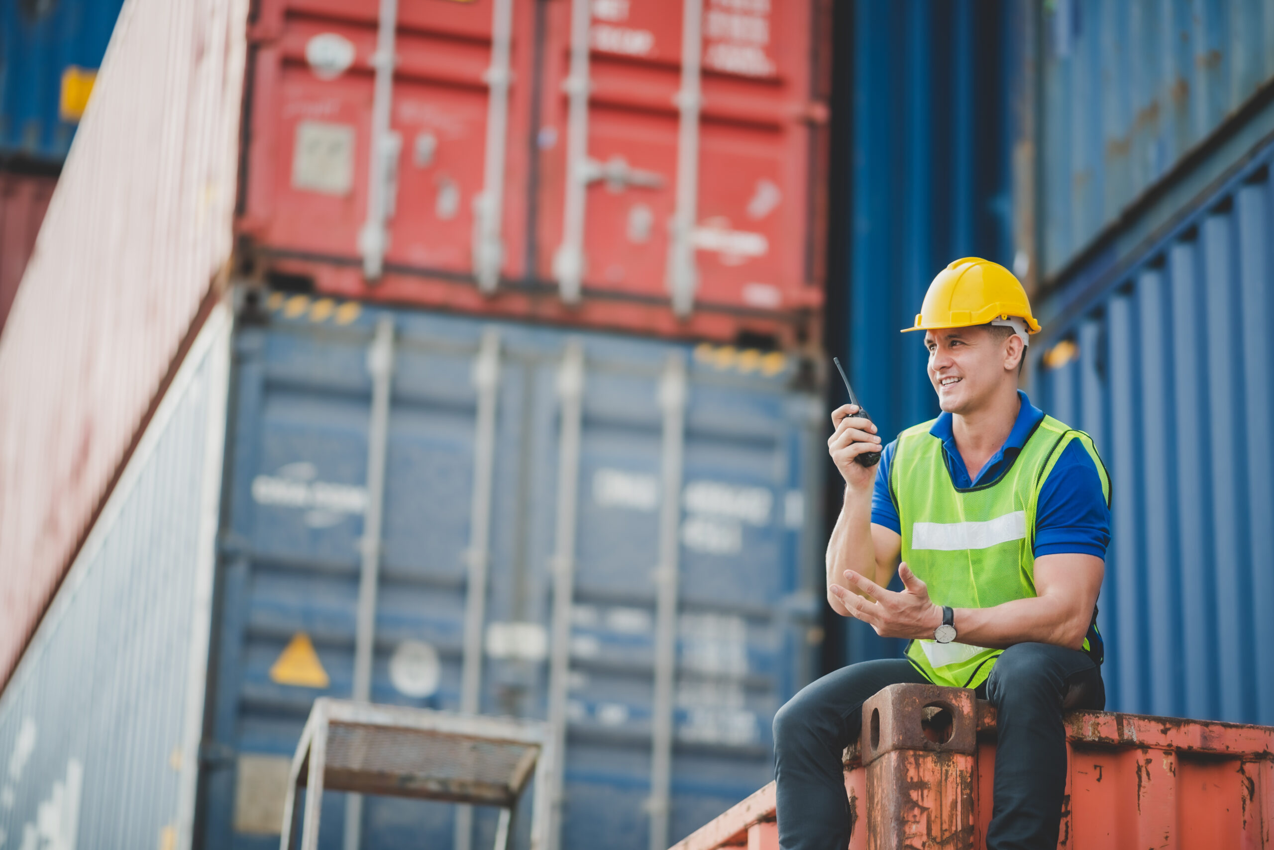 foreman worker manager working outdoor site, cargo container site, control plan working, working with safety equiments, helmet safety vest, technology walkie talkie concept.pointing finger